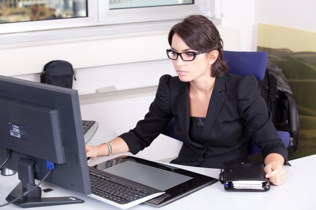 Девушка в очках работает в офисе на компьютере.